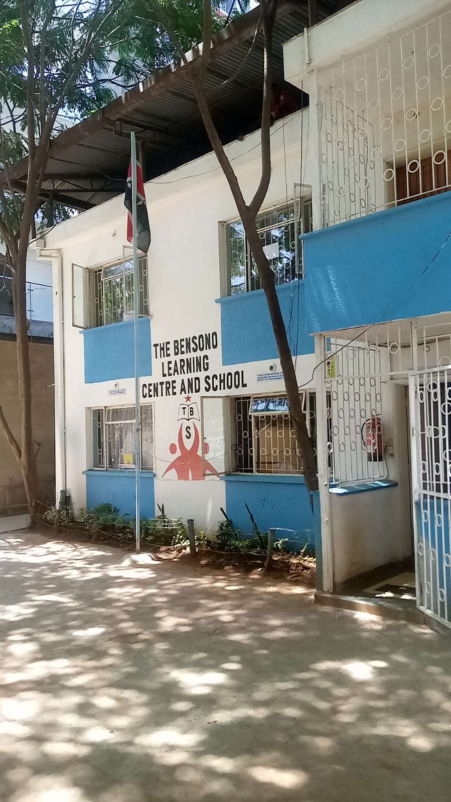 Exterior view of bensono learning centre and school kenyan flag and entrance to classrooms